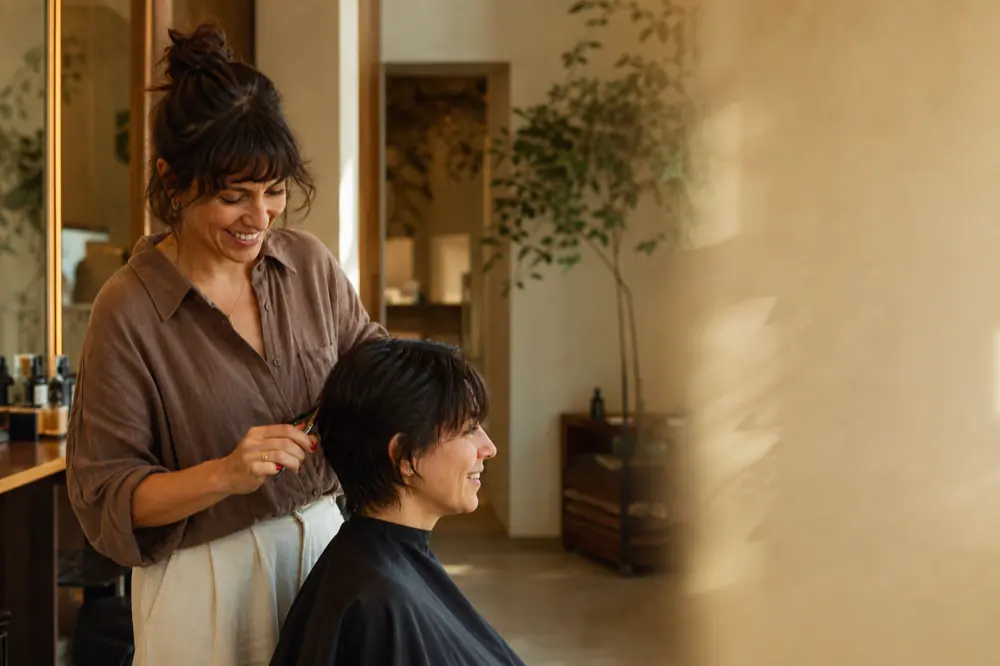 Cabeleireiro finalizando o corte de uma cliente em um salão de beleza