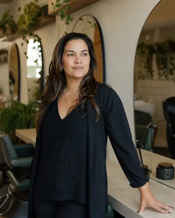 Dona de salão sorrindo ao lado da estação de atendimento